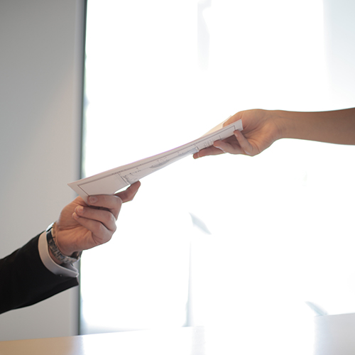 person handing papers to colleague
